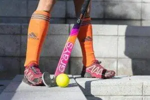 Close-up of a field hockey player with a stick and ball on stone steps.