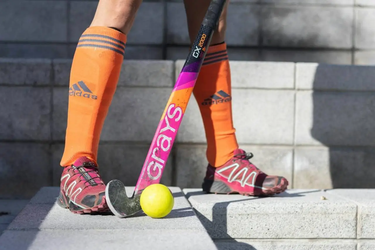 Close-up of a field hockey player with a stick and ball on stone steps.