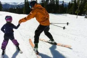 a woman teaching a child how to ski