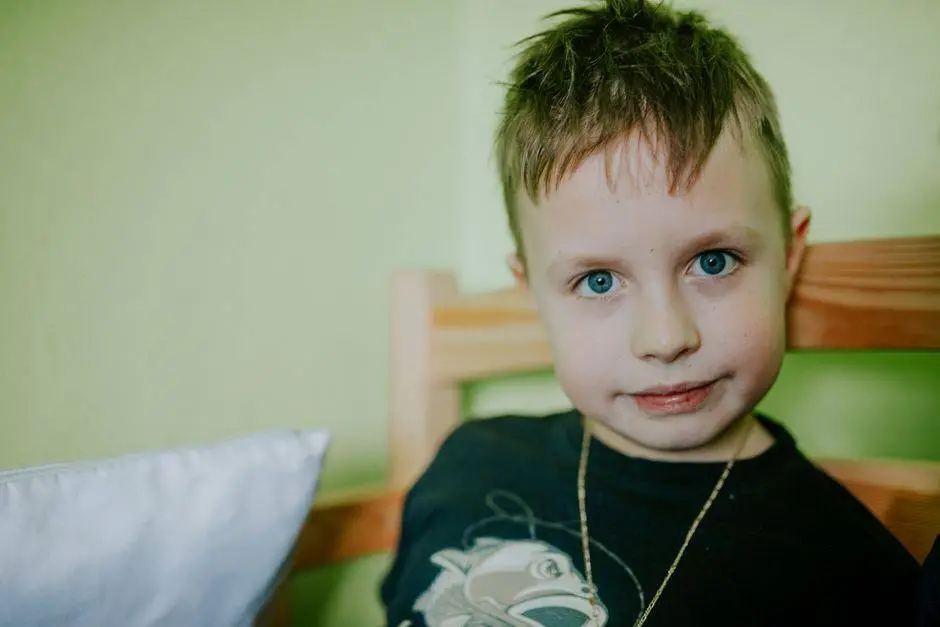 Portrait of a young boy with blue eyes wearing a t-shirt, indoors with a light green background.