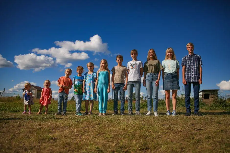 A diverse group of children and teenagers smiling under a sunny blue sky, showcasing unity and happiness.