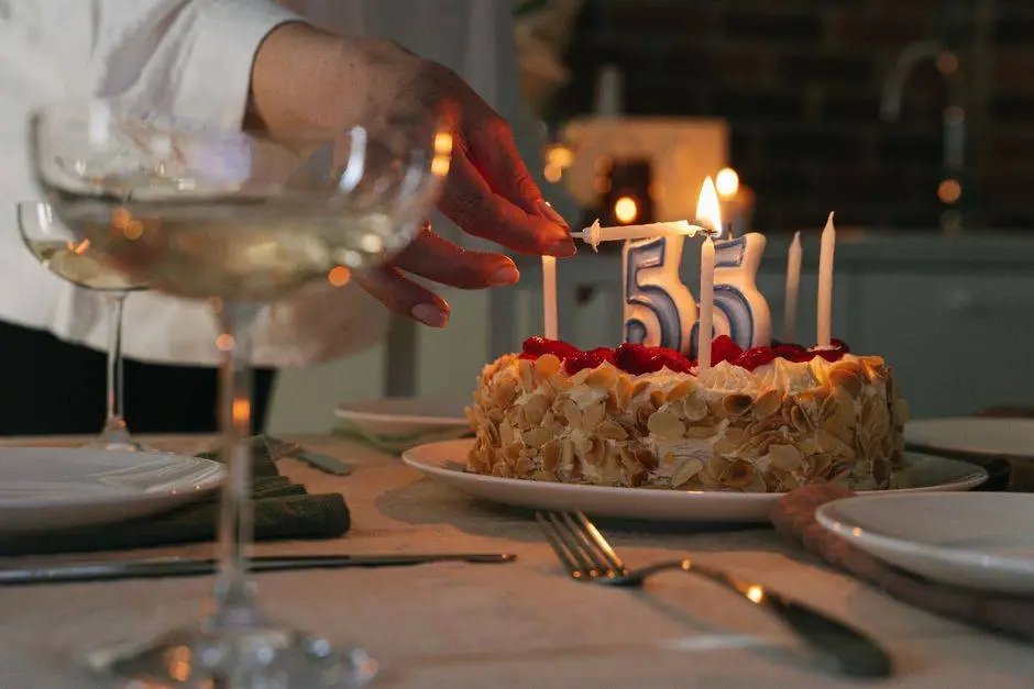 A close-up of a cake with candles celebrating a 55th birthday, set in a cozy indoor setting.