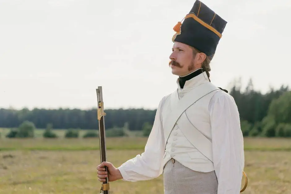 Man in historical attire posing with rifle during outdoor reenactment.