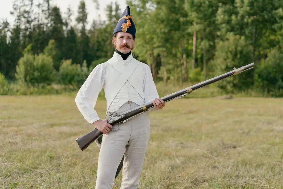 Man dressed in historical uniform with musket in a field setting.